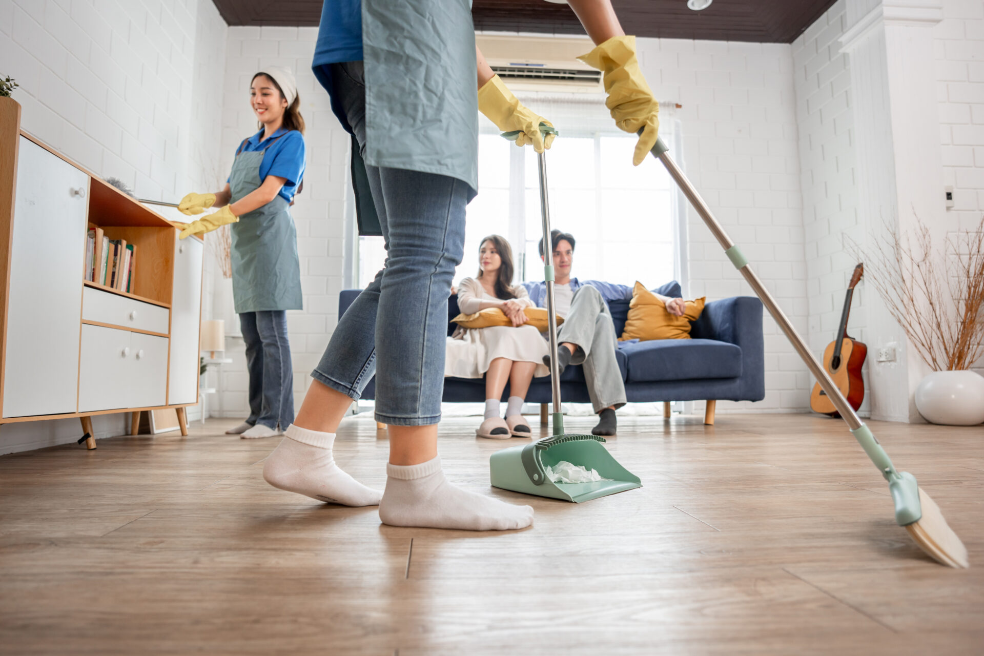 Asian cleaner team cleaning living room at home for new couple customer. Attractive girls housewife housekeeper feeling happy and relax, enjoy doing housekeeping housework or chores for house owner.