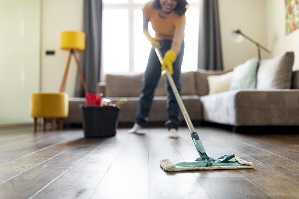 smiling-young-woman-washing-floor-in-living-room-w-2025-03-18-16-41-56-utc